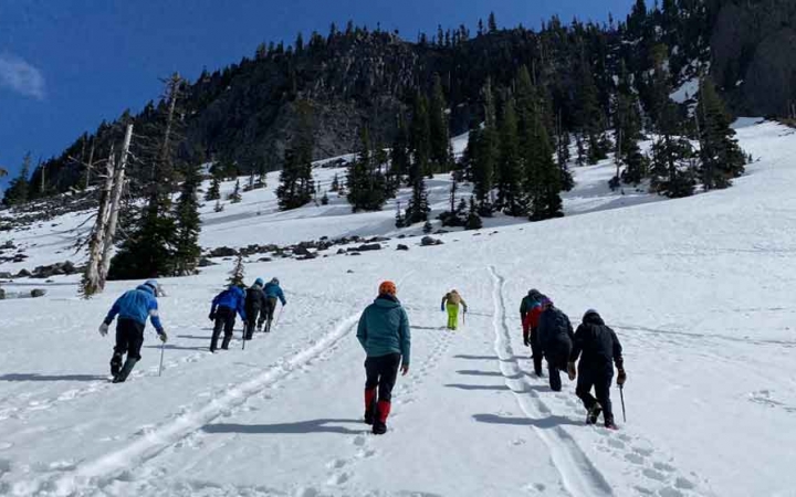 a group of gap year students ascend a snowy incline on an outward bound outdoor educator course